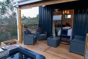 Casa con terraza con sillas y dormitorio en The Surfers Bush Cabin, en Jeffreys Bay