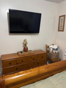 um quarto com uma cómoda e uma televisão de ecrã plano na parede em Victorian Palace-Pecan Room em East Orange