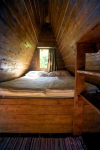 1 cama en una cabaña de madera con ventana en Baba Yagas house, en Rakhiv