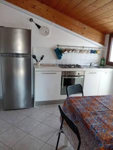 una cucina con frigorifero in acciaio inossidabile e tavolo di Accogliente appartamento mansardato vicino al mare a Tortoreto