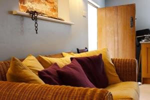 un sofá con almohadas amarillas y moradas. en Deepmoor Farmhouse, Doveridge, Derbys., en Doveridge