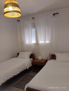 a room with two beds and a window and a chandelier at SnD Rentals -Boutique apartments in Kozani