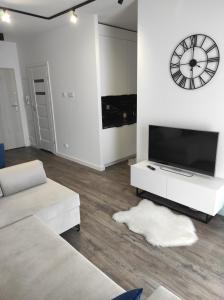 a living room with a tv and a clock on the wall at Klonowa 65 z garażem podziemnym in Kielce