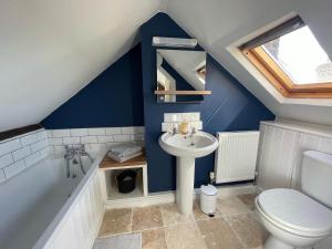 a bathroom with a sink and a toilet and a tub at Stylish 2 bedroom apartment close to beaches in Fakenham