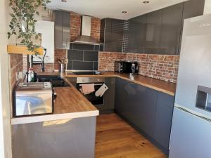 a kitchen with gray cabinets and a brick wall at Stylish 2 bedroom apartment close to beaches in Fakenham
