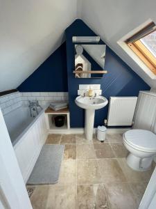 La salle de bains est pourvue d'un lavabo, d'une baignoire et de toilettes. dans l'établissement Stylish 2 bedroom apartment close to beaches, à Fakenham