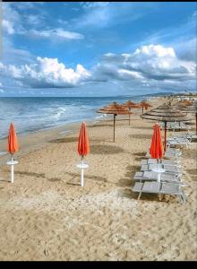 una spiaggia con sedie e ombrelloni e l'oceano di Accogliente appartamento mansardato vicino al mare a Tortoreto