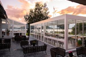 un restaurante con paredes de cristal, mesas y sillas en Rosendal Fjordhotel, en Rosendal