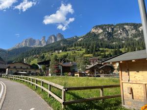 a village with a fence and mountains in the background at Mes Lastei in Campitello di Fassa