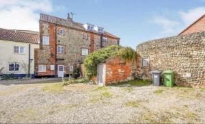 an old brick building with two trash cans in front of it at Stylish 2 bedroom apartment close to beaches in Fakenham