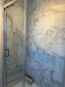 e bagno con doccia e parete in marmo. di Design-led flat in Hampstead a Londra