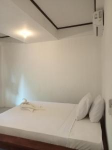 un letto con lenzuola e cuscini bianchi in una stanza di Putra Boyan Cottages a Gili Trawangan