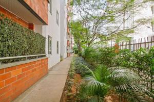 an empty sidewalk next to a brick building with plants at studio 14 in Medellín