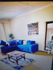 Sala de estar con sofá azul y mesa de centro en Sapphire Guest House en Germiston