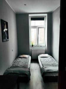 two beds in a room with a window at Pokoje gościnne w centrum in Wałbrzych
