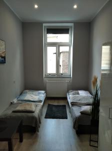 two beds in a room with a window at Hostel Rycerska in Wałbrzych