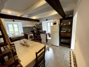 eine Küche mit einem Tisch und einem weißen Kühlschrank in der Unterkunft Gîte du Pays-de-Salers, Cantal, classé 1* in Saint-Projet-de-Salers