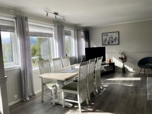 a dining room with a table and chairs and windows at Romslig leilighet i Lofoten 