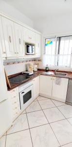 a kitchen with white cabinets and white tile floors at Bungalow mit Meerblick in Costa Calma