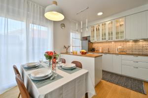 a kitchen with a dining table and a kitchen with white cabinets at Apartment Zicer in Zagreb