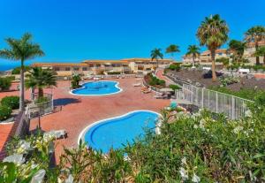 een uitzicht op een resort met 2 zwembaden en palmbomen bij Sunny Garden 1 BR Apartment Arona in Playa de las Americas