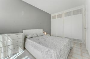 a white bedroom with a bed and a dresser at Sunny Garden 1 BR Apartment Arona in Playa de las Americas