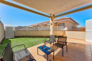 een patio met stoelen en een tuin met een huis bij Sunny Garden 1 BR Apartment Arona in Playa de las Americas