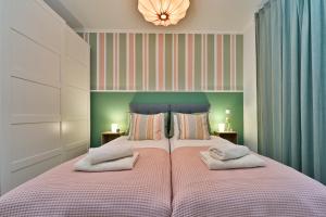 a bedroom with a pink bed with two towels on it at Apartment Zicer in Zagreb