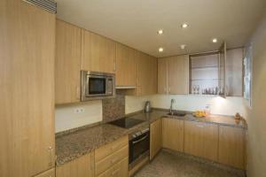 uma cozinha com armários de madeira, um lavatório e um micro-ondas em Spacious Stunning Views 2-Bed Apartment Estepona em Estepona
