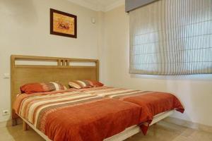 um quarto com uma cama grande com lençóis laranja e uma janela em Spacious Stunning Views 2-Bed Apartment Estepona em Estepona