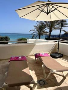 duas cadeiras e um guarda-sol num pátio com o oceano em Spacious Stunning Views 2-Bed Apartment Estepona em Estepona