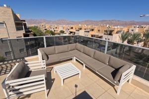 d'une terrasse avec un canapé et des chaises sur un balcon. dans l'établissement YalaRent Villa Dolina with private pool, à Eilat