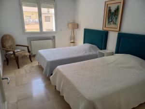 een kamer met 2 bedden, een stoel en een raam bij Cozy Inn Lac 2 in Tunis