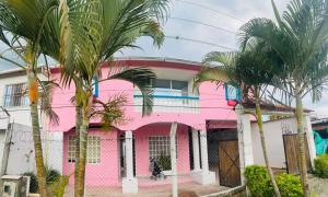 una casa rosa con palmeras delante en Finca hotel casa rosada, en Tuluá