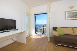 a living room with a tv and a couch and a balcony at Apartments Stipe Plazibat in Hvar
