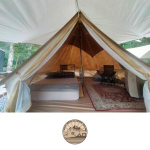a tent with a bed and a table in it at Tanah Merah Glamping Village (TMGV) in Kuala Kangsar