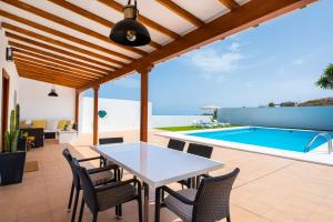 un patio con una mesa y sillas blancas y una piscina en Private house with pool & garden en Güimar