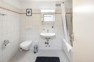ein weißes Bad mit einem Waschbecken und einem WC in der Unterkunft habu bei Plättli Zoo cosy stay in Frauenfeld