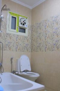 a bathroom with a toilet and a window with a fan at شقة فاخرة علي البحر مباشرة لوران الاسكندرية in Alexandria