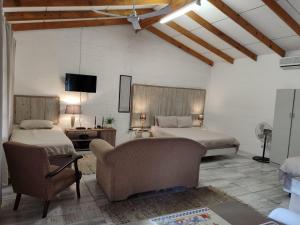 a bedroom with two beds and a couch and a tv at Numbi Hills Self-Catering in Hazyview