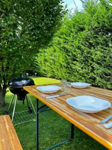 einem Holztisch mit weißen Tellern und einem Grill in der Unterkunft Dea Igea Apartment in Bellaria-Igea Marina
