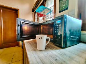 eine Mikrowelle und eine Kaffeetasse auf einer Theke in der Unterkunft UVs Homestay in Haridwar