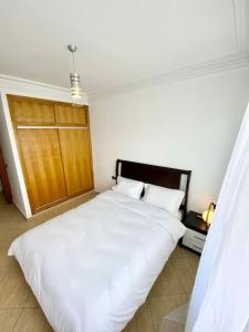 um quarto com uma cama branca e uma porta de madeira em Appartement au cœur de Rabat em Rabat