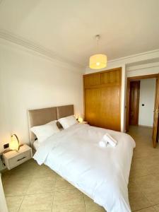 um quarto com uma grande cama branca e uma cabeceira em madeira em Appartement au cœur de Rabat em Rabat