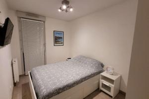 Habitación pequeña con cama y mesita de noche en Appartement Voie Lactée Lyon, en Lyon