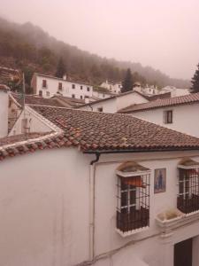 a white building with two windows and a mountain at Hotel Casa de las Piedras in Grazalema