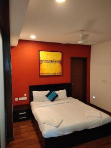 a bedroom with a large bed with a red wall at Goan Fiesta 1BHK Pool View at Eternal Wave CALANGUTE in Calangute