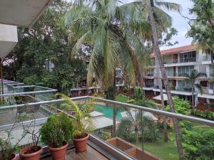 an apartment balcony with palm trees and a swimming pool at Goan Fiesta 1BHK Pool View at Eternal Wave CALANGUTE in Calangute
