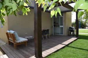 una terraza de madera con una silla y una mesa en Matmon Barava, en ‘En Yahav