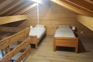two beds in a room with wooden walls at Gîte Les sepneilles ! in Gérardmer
